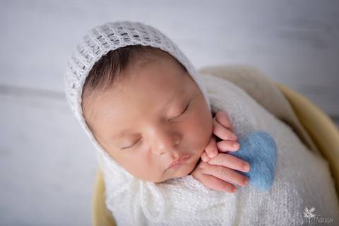 bebê recém nascido newborn brasilia fotografa fotografo fotógrafa brasília df distrito federal baby bebe reborn book melhor leticia franco menino no tecido wrap branco com touquinha branca na madeira branca com coração azul na mão'