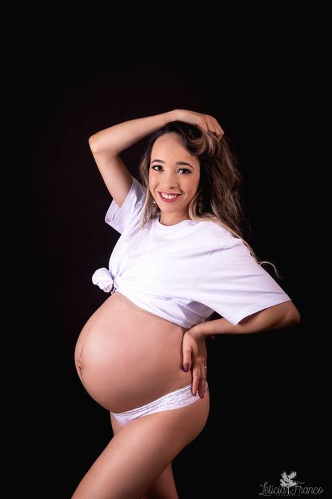 ensaio gestante mamãe fotografa fotógrafa brasília df distrito federal baby bebe reborn book melhor leticia franco letícia estúdio  gestante com a mão no cabelo e na barriga blusa branca fundo preto mão no cabelo sorrindo'