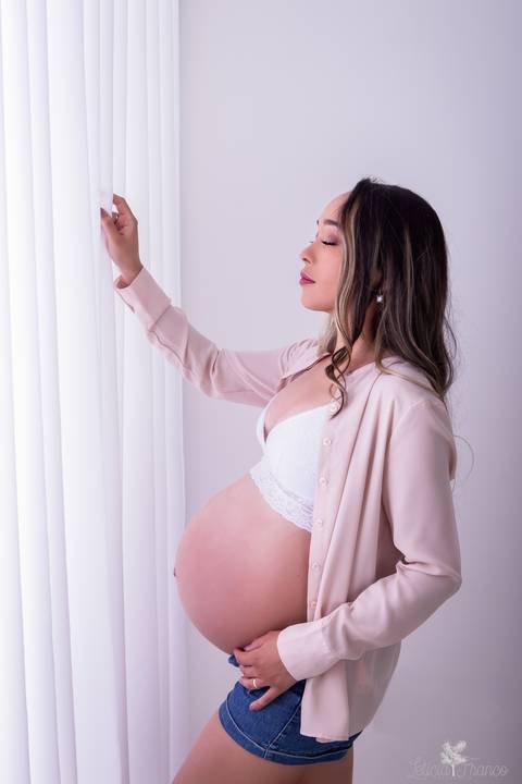 ensaio gestante mamãe fotografa fotógrafa brasília df distrito federal baby bebe reborn book melhor leticia franco letícia estúdio  gestante com a mão no cabelo e na barriga fundo branco lingerie branca com a mão na cortina'