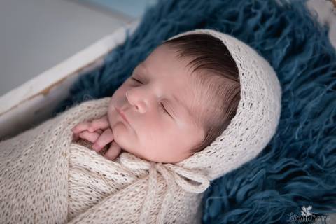 bebê recém nascido newborn brasilia fotografa fotografo fotógrafa brasília df distrito federal baby bebe reborn book melhor leticia franco menino enrroladinho no tecido branco com fundo azul bercinho com touca'