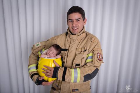 bebê recém nascido newborn brasilia fotografa fotografo fotógrafa brasília df distrito federal baby bebe reborn book melhor leticia franco menino no capacete de bombeiro cmbdf com papai segurando'