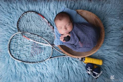 bebê recém nascido newborn brasilia fotografa fotografo fotógrafa brasília df distrito federal baby bebe reborn book melhor leticia franco menino enrroladinho no tecido branco com fundo azul bercinho com touca com raquete e bola de squash'