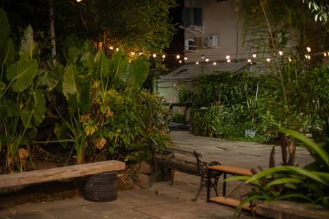 Alt Text: paisagem verde com luminárias suspensas e bancos de madeira'