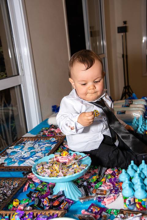 Foto do Aniversariantes na Mesa de Doces com Um Dadinho na Mão Na Vila Andrade - SP. Foto por Priscila Felix, fotógrafa de família, ensaios, eventos e casamentos.'