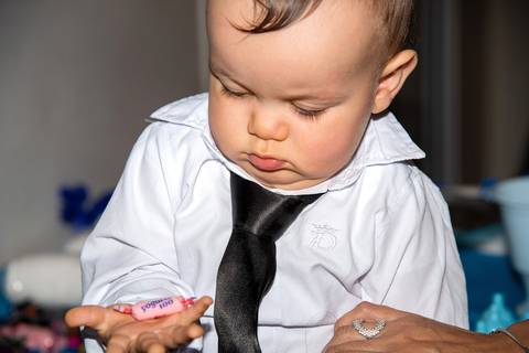 Foto do Aniversariante Olhando Curiosamente Para uma Bala em Sua Mão Na Vila Andrade - SP. Foto por Priscila Felix, fotógrafa de família, ensaios, eventos e casamentos.'