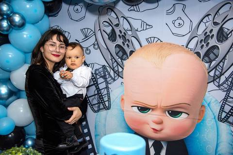 Foto da Mãe Com O Aniversariante na Mesa do Bolo Com O Pequeno Chefinho Ao Fundo Na Vila Andrade - SP. Foto por Priscila Felix, fotógrafa de família, ensaios, eventos e casamentos.'