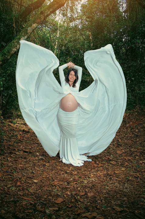 Foto da Mãe de Frente Usando Um Vestido Longo Branco Com a Barriga de Fora Abrindo a Capa Para as Laterais Formando Um Coração No Núcleo Engordador Na Cantareira em São Paulo, Foto Feita Pela Priscila Felix Fotógrafa de Família, Casamento e Ensaios '