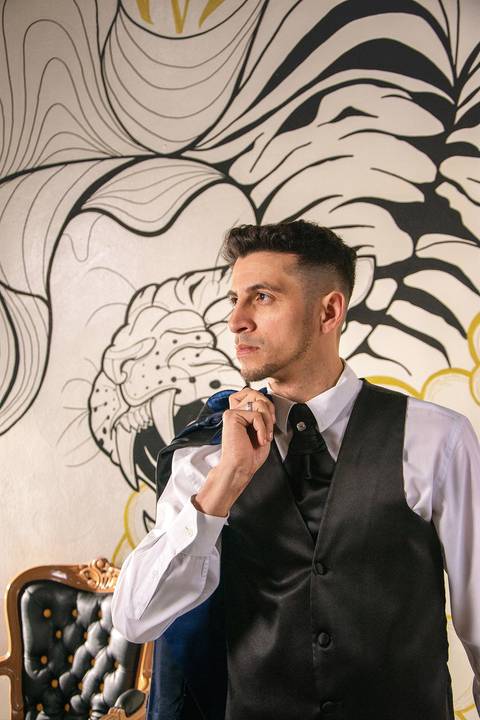 Fotografia do Noivo de Perfil com o Paletó no Ombro na Barbearia Be King em Guarulhos SP Feita por Priscila Felix Fotógrafa de Casamentos, Ensaios e Família'