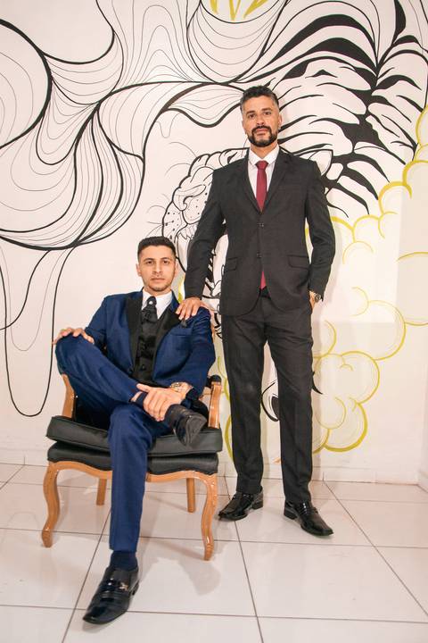 Fotografia do Noivo Sentado e ao Seu Lado o Irmão em Pé com a Mão no Ombro do Noivo na Barbearia Be King em Guarulhos SP Feita por Priscila Felix Fotógrafa de Casamentos, Ensaios e Família'