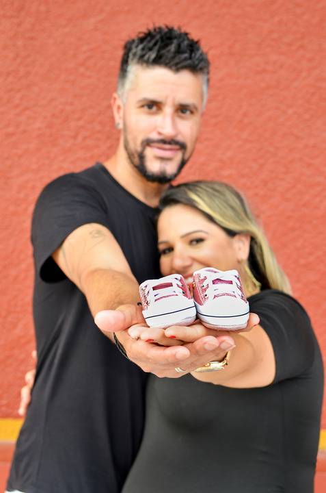 Foto dos Pais Segurando os Sapatinhos nas Mãos e Mostrando, Os Pais Desfocados e o Sapato em Foco em Guararema - SP, Foto Feita Pela Priscila Felix Fotógrafa de Família, Casamento e Ensaios '