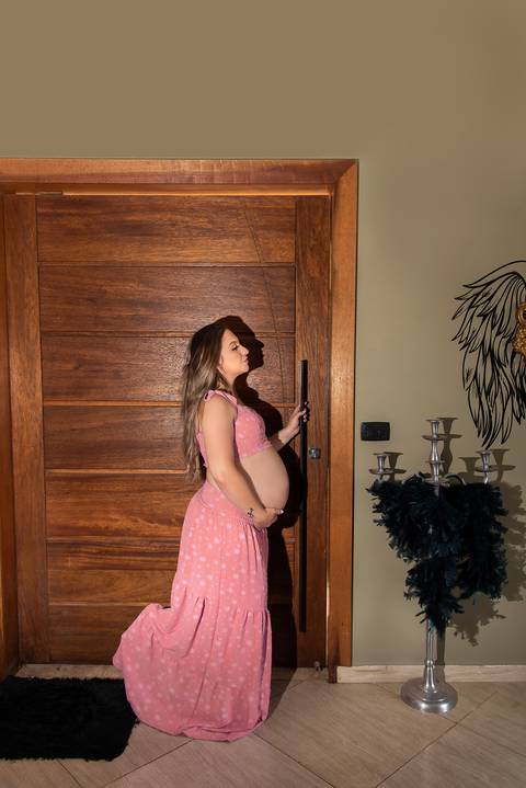 Foto da Mãe de Perfil Em Frente à uma Grande Porta de Madeira Usando Uma Saia Longa e Um Top Cor de Rosa em São Paulo - SP, Foto Feita Pela Priscila Felix, Fotógrafa de Família, Casamento e Ensaios '