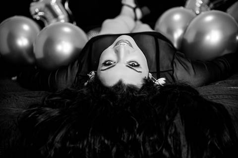 Foto Em Preto e Branco da Filha Na Cama De Barriga Pra Cima Olhando Pra Trás Com Cocha Preta, Roupa Preta Com Balões Numerais 32 Dourados de Seu Aniversário em São Paulo - SP, Foto Feita Pela Priscila Felix, Fotógrafa de Família, Casamento e Ensaios '