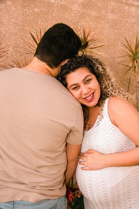 Foto da Mãe Sorrindo Apoiando o Rosto no Ombro do Pai No Jardim do Apartamento em Itaquera - SP, Foto Feita Pela Priscila Felix Fotógrafa de Família, Casamento e Ensaios '