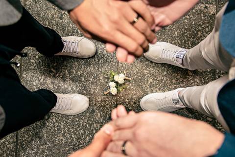 Foto das Mãos do Casal de Cima para Baixo Entre as Mãos No Chão Estão as Flores do Paletó Na Estação da Luz em São Paulo - SP, Foto Feita Pela Priscila Felix Fotógrafa de Família, Casamento e Ensaios '