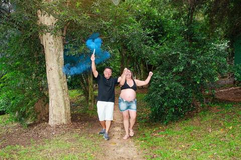 Foto do Casal Correndo Com Fumaça Azul Anunciando a Chegada do Samuel Com Muita Alegria No Bosque Maia em Guarulhos - SP, Foto Feita Pela Priscila Felix Fotógrafa de Família, Casamento e Ensaios '