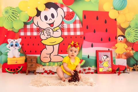 Fotografia da Bebê Pegando o Cacho de Uva Olhando Curiosa no Estúdio Com Cenário da Magali da Turma da Monica em SP Feita por Priscila Felix Fotógrafa de Casamentos, Ensaios e Família'