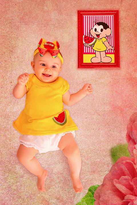 Fotografia da Bebê Deitada de Barriguinha Pra Cima Sorrindo no Estúdio Com Cenário da Magali da Turma da Monica em SP Feita por Priscila Felix Fotógrafa de Casamentos, Ensaios e Família'