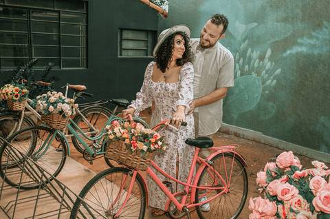 Foto dos Noivos Sorrindo E Se Olhando Com a Bicicleta De Cestinha Com Flores Ensaio Casal Pre Wedding Em Holambra SP, feita pela Priscila Felix, fotógrafa de casamentos, ensaios e eventos'