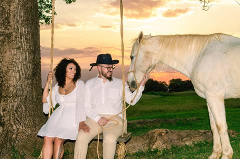 Foto dos Noivos Num Balanço Acarinhando Um Cavalo Branco No Sítio Essência do Campo Ensaio Casal Pre Wedding Em Holambra SP, feita pela Priscila Felix, fotógrafa de casamentos, ensaios e eventos'