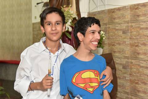 Fotografia do Batizado Segurando a Vela e Com o Terço no Pescoço Abraçando o Irmão Em Frente a Imagem de São José Na Igreja São José em São Paulo, SP Feita por Priscila Felix Fotógrafa de Casamentos, Ensaios e Família'