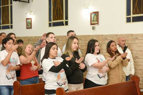 Fotografia dos Crismados de Olhos Fechados Com As Mãos Estendidas Em Direção Ao Altar Na Igreja São José em São Paulo, SP Feita por Priscila Felix Fotógrafa de Casamentos, Ensaios e Família'