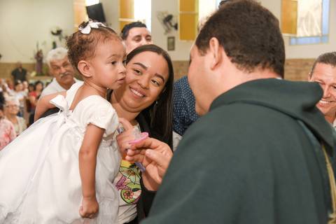 Fotografia do Padre Passando o Óleo no Peito da Batizada No Colo da Madrinha Na Igreja São José em São Paulo, SP Feita por Priscila Felix Fotógrafa de Casamentos, Ensaios e Família'