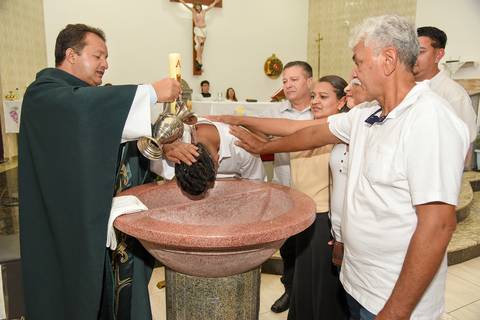 Fotografia do Padre Jogando a Água na Cabeça do Batizado e Toda a Família Em Volta da Pia Batismal Na Igreja São José em São Paulo, SP Feita por Priscila Felix Fotógrafa de Casamentos, Ensaios e Família'