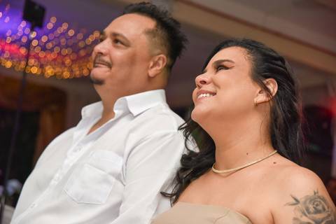 Foto do Aniversariante E Esposa Sorrindo Assistindo a Retrospectiva No Telão No Buffet Em São Paulo - SP, Foto Feita Pela Priscila Felix Fotógrafa de Família, Casamento e Ensaios '