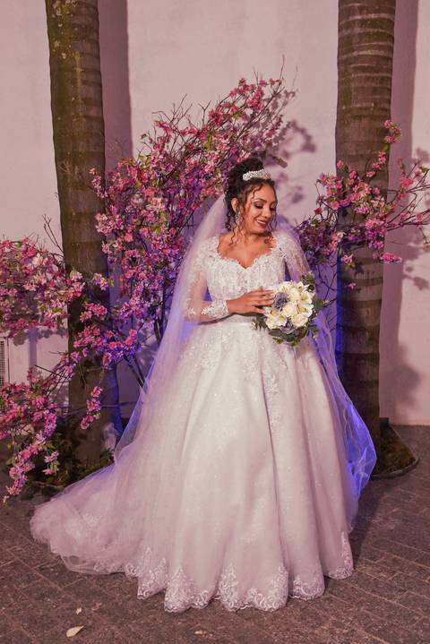 Fotografia da Noiva Segurando o Bouquet No Jardim Com Uma Luz na Cor Roxa Iluminando Atras em Mansão Pimenta Nativa Salão de Festas no Tatuapé - SP Feita por Priscila Felix Fotógrafa de Casamentos, Ensaios e Família'