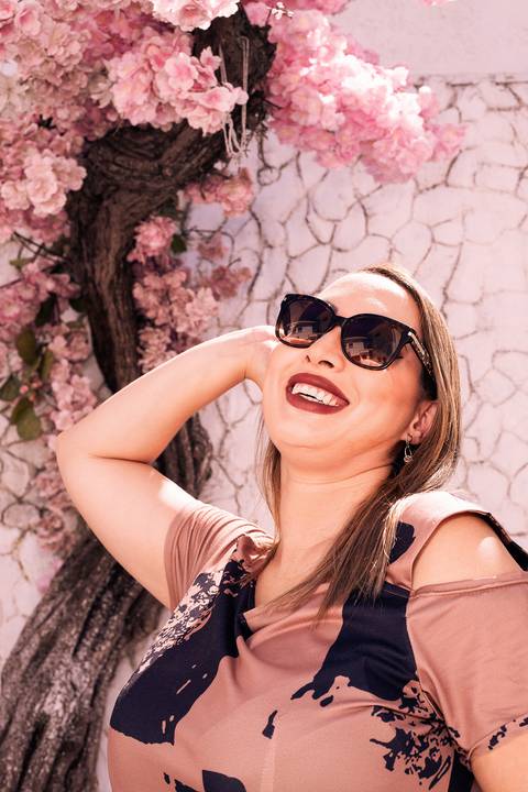 Foto da Modelo No Cenário Grécia, Sorrindo Com a Mão Nos Cabelos Em Frente à Cerejeira No Estúdio Noma Conecta No Ipiranga em São Paulo - SP, Foto Feita Pela Priscila Felix Fotógrafa de Família, Casamento e Ensaios '
