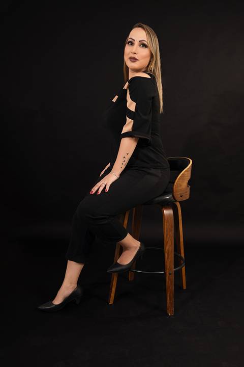 Foto da Modelo No Estúdio Com Fundo Preto Sentada Numa Banqueta Usando Calça e Blusa Preta No Estúdio Noma Conecta No Ipiranga em São Paulo - SP, Foto Feita Pela Priscila Felix Fotógrafa de Família, Casamento e Ensaios '