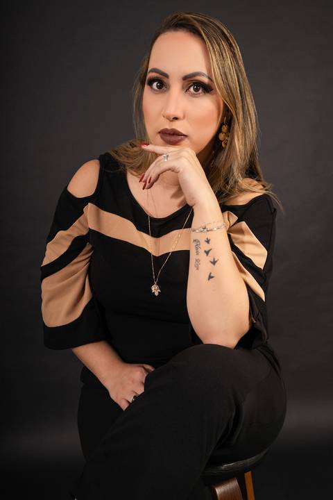 Foto da Modelo No Estúdio Com Fundo Preto Sentada Numa Banqueta Com a Mão Em Frente Ao Queixo Olhando Para a Frente No Estúdio Noma Conecta No Ipiranga em São Paulo - SP, Foto Feita Pela Priscila Felix Fotógrafa de Família, Casamento e Ensaios '