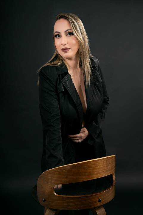 Foto da Modelo No Estúdio Com Fundo Preto Usando Calça e Casado Pretos Com a Mão Na Banqueta No Estúdio Noma Conecta No Ipiranga em São Paulo - SP, Foto Feita Pela Priscila Felix Fotógrafa de Família, Casamento e Ensaios '