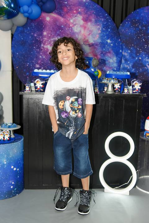 Foto do Aniversariante Em Frente à Mesa do Bolo Com as Mãos Nos Bolsos No Espaço Castelli e Campos Buffet em Guarulhos - SP, Foto Feita Pela Priscila Felix Fotógrafa de Família, Casamentos e Ensaios '