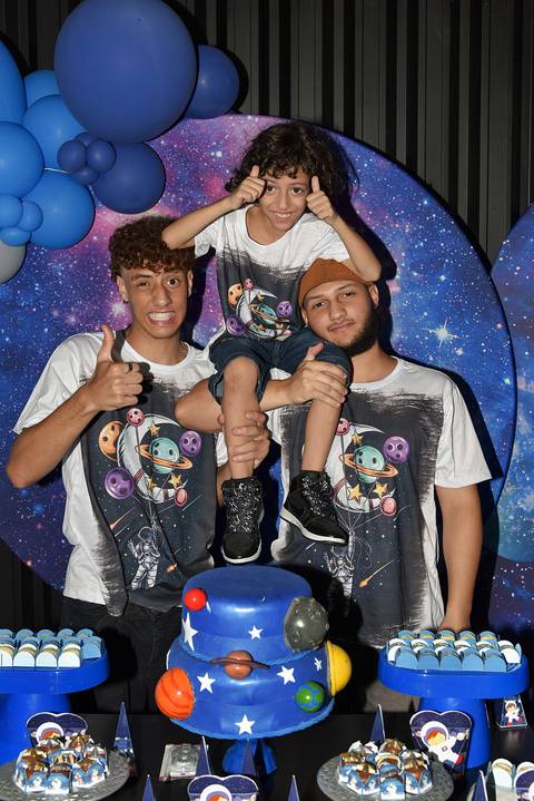 Foto dos Irmãos Com o Aniversariante Nos Ombros Atrás da Mesa do Bolo No Espaço Castelli e Campos Buffet em Guarulhos - SP, Foto Feita Pela Priscila Felix Fotógrafa de Família, Casamentos e Ensaios '