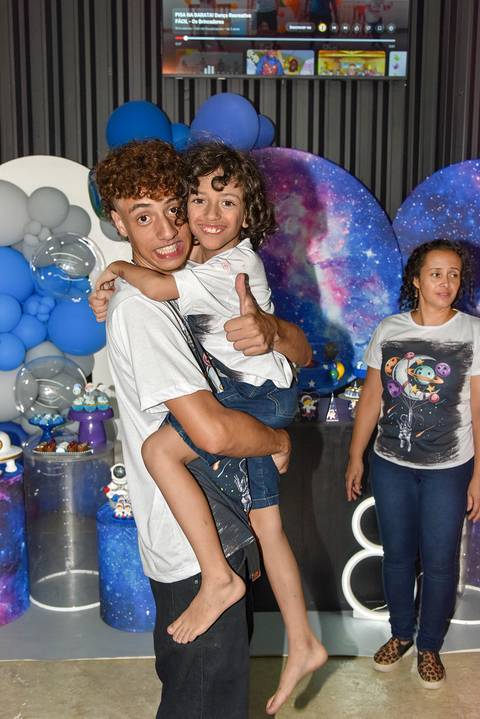 Foto do Aniversariante No Colo do Irmão Sorrindo e Fazendo Joinha No Espaço Castelli e Campos Buffet em Guarulhos - SP, Foto Feita Pela Priscila Felix Fotógrafa de Família, Casamentos e Ensaios '