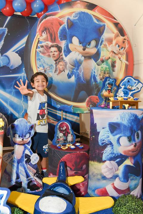 Foto do Aniversariante Em Frente a Decoração do Sonic Mostrando sua Idade Com a Mão Aberta, Cinco Anos, No Buffet Festas & Cia Na Mooca - SP, Foto Feita Pela Priscila Felix Fotógrafa de Família, Casamentos e Ensaios '