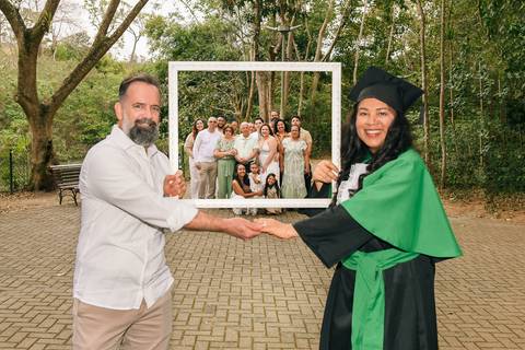 Foto da Formanda Segurando Uma Moldura Junto Com O Marido E, Ao Fundo, Dentro da Moldura Todos Os Parentes No Parque do Pau D´Alho Em Guararema - SP, Foto Feita Pela Priscila Felix, Fotógrafa de Família, Casamento e Ensaios '