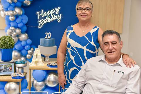 Fotografia do Aniversariante Sentado Na Frente Da Mesa Do Bolo Com Sua Esposa Ao Lado no Tatuapé SP Feita por Priscila Felix Fotógrafa de Casamentos, Ensaios e Família'