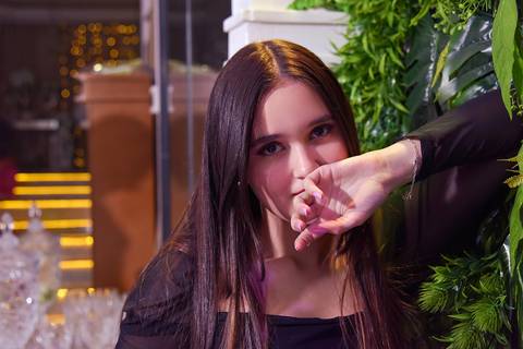 Foto da Debutante Com A Mão Em Frente a Boca Apoiando o Braço No Painel Verde No Buffet Marron Glacê Em São Mateus - SP, Foto Feita Pela Priscila Felix Fotógrafa de Família, Casamentos e Ensaios '