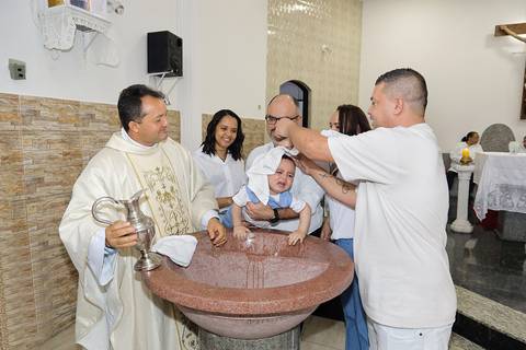 Fotografia Do Batizado Na Pia Batismal Chorando Enquanto o Padrinho Enxuga A Cabeça Do Bebê Após O Batismo Com A Água Na Igreja São José em São Paulo, SP Feita por Priscila Felix Fotógrafa de Casamentos, Ensaios e Família'