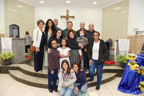 Fotografia Da Batizada Segurando A Vela Do Batismo Ao Lado Do Padre E Toda Sua Família No Altar Da Igreja São José em São Paulo, SP Feita por Priscila Felix Fotógrafa de Casamentos, Ensaios e Família'