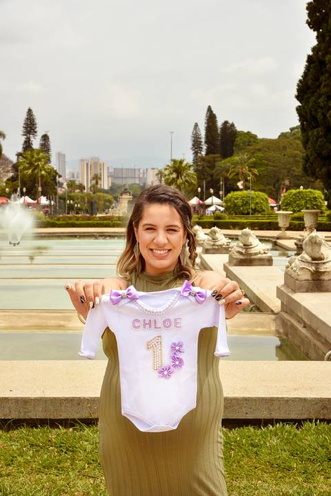 Foto da Mãe Mostrando O Body Com o Nome da Filha Bordado e Ao Fundo O Jardim do Ipiranga No Parque Da Independência em São Paulo - SP, Foto Feita Pela Priscila Felix Fotógrafa de Família, Casamento e Ensaios '