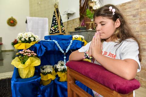 Fotografia Da Catequizada Ajoelhada No Oratório Com As Mãos Juntas Na Frente Do Rosto Na Igreja São José em São Paulo, SP Feita por Priscila Felix Fotógrafa de Casamentos, Ensaios e Família'