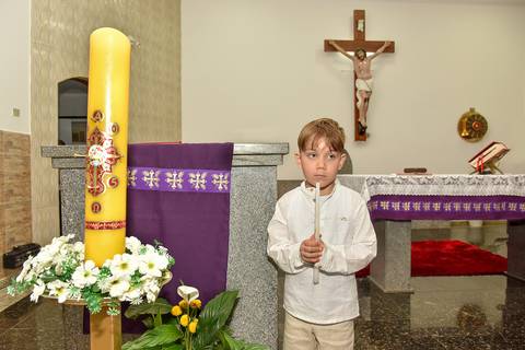 Fotografia Do Batizado No Altar Segurando A Vela Ao Lado Do Círio Batismal Na Igreja São José em São Paulo, SP Feita por Priscila Felix Fotógrafa de Casamentos, Ensaios e Família'