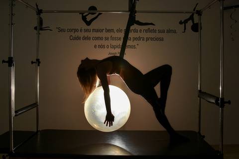 Foto da Silhueta da Modelo Pendurada No Cadillac, Segurando A Bola de Pilates Nas Costas Iluminada, Como Se Fosse a Lua, No Estúdio De Pilates  em São Paulo - SP, Foto Feita Pela Priscila Felix Fotógrafa de Família, Casamento e Ensaios '