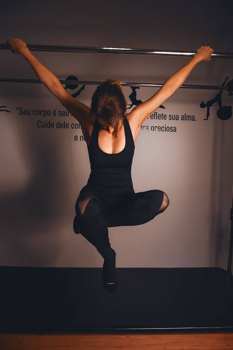 Foto da Modelo Pendurada Na Barra do Cadillac, Cruzando As Pernas No Ar, No Estúdio De Pilates  em São Paulo - SP, Foto Feita Pela Priscila Felix Fotógrafa de Família, Casamento e Ensaios '