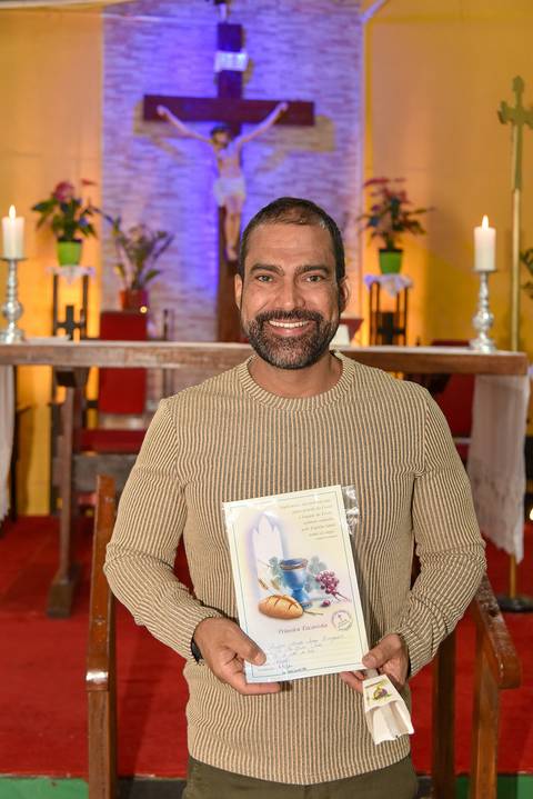 Fotografia Do Rafael Sorrindo Segurando O Certificado Da 1ª Comunhão Na Paróquia São Judas Tadeu em São Paulo, SP Feita por Priscila Felix Fotógrafa de Casamentos, Ensaios e Família'