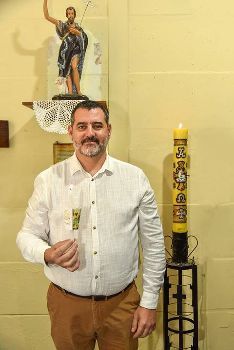 Fotografia Do Padrinho Do Theo Com A Vela Acesa Ao Lado Do Círio Batismal Na Paróquia São Judas Tadeu em São Paulo, SP Feita por Priscila Felix Fotógrafa de Casamentos, Ensaios e Família'
