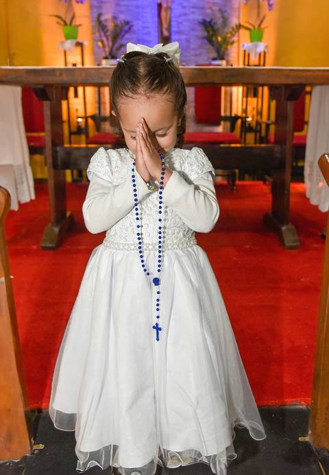 Fotografia Da Manuella Segurando O Terço De Mãos Junstas Postas Na Testa Na Paróquia São Judas Tadeu em São Paulo, SP Feita por Priscila Felix Fotógrafa de Casamentos, Ensaios e Família'